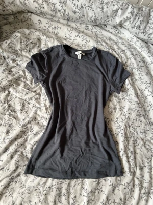 Grå tight t-shirt - En mjuk och fin figursydd t-shirt som är grå från H&M, för dig som vill ha en tight fit  och en mjuk känsla på kroppen. Passar perfekt för en casual clean look eller för gymmet. Säljer för att jag använt den 1 gång bara och köptes för ca 200kr. 