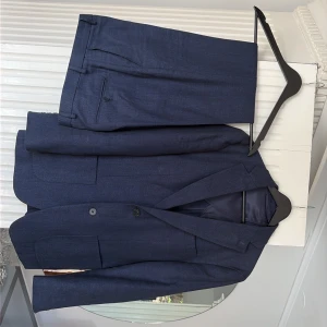 Marinblå Linnekostym - Säljer en marinblå Linnekostym från John Henric. Endast använd vid ett tillfälle. Kavajen är i strl. 44 och byxorna i w44. Nypris hos John Henric är 2500 kr. Kontakta för fler frågor!