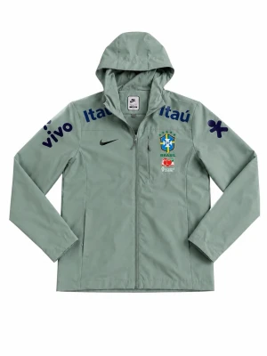 Nike Brasil vindjacka med huva - Ljusgrön vindjacka från Nike med huva och dragkedja. Jackan har Brasil-logga, svarta och blå tryck på bröst och ärmar samt meshfoder. Perfekt för sportiga dagar och streetwear. Sponsormärken som Itaú och Vivo ger en unik look.