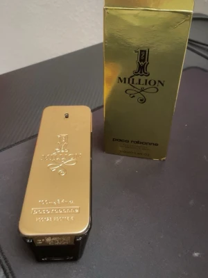 Paco Rabanne 1 Million EdT 100ml - 1 Million från Paco Rabanne är en ikonisk herrparfym i en lyxig guldfärgad flaska som liknar en guldtacka. Flaskan är rektangulär med guldfärgad metall på framsidan och mörkbrun plast på sidorna. Kommer med originalförpackning i matchande guld.