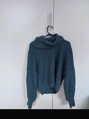 Mörkgrön stickad polotröja - Mysig mörkgrön stickad tröja med bred polokrage och avslappnad passform. Tröjan har långa ärmar och ribbstickad struktur, perfekt för kyliga dagar. Passar dig som gillar en enkel men trendig look.