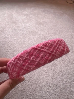 Rosa tweeddiadem med glitter - Säljer ett fluffigt diadem i rosa tweed med inslag av silverglitter. Diademet har en bred form och ett rutigt mönster i olika rosa nyanser. Perfekt för att ge en söt och trendig touch till din look.