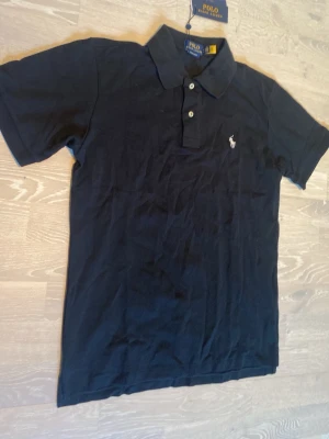 Svart  pikétröja från Polo Ralph Lauren - Tja! Säljer en helt ny svart Ralph Lauren Piké.                      Den är helt ny och har inga hål eller fläckar.                                Storlek M och måtten kan du se på dem sista bilderna📐.                                                                              Priset kan diskuteras och jag skickar inom 24 Tim☺️💨