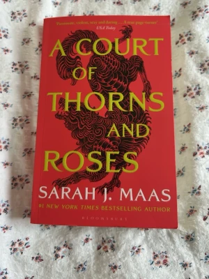 A Court of Thorns and Roses - En fantasyroman skriven av Sarah J. Maas. Boken är på engelska. Aldrig läst. Perfekt för dig som gillar romantik, äventyr och magi i en episk värld.