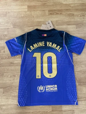 FC Barcelona bortaställ 26/27 - Bortaställ för FC Barcelona under den kommande säsongen 26/27 med Lamine Yamal 10 på ryggen. Den är i färgen blå/lila. Hög kvalité och helt ny!!