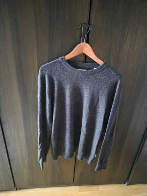 Mörkgrå stickad tröja Jack & Jones - Mörkgrå stickad tröja från Jack & Jones i ullblandning. Klassisk rund halsringning och långa ärmar. Enkel och stilren design som passar perfekt till lager-på-lager eller för en clean look.
