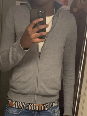 Grå Pier one full zip. - Pier one full zip, extremt clean med många fina detaljer som dubbel drag kedja, mörkblå på insidan av kragen. Den är inprincip nyskick. Modellen är 180 cm 75 kg och bär storlek M passar även storlek S skulle jag säga. Hör av dig om du har frågor!