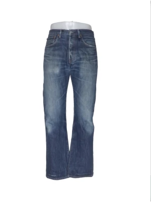 Levis 501 Jeans  - Säljer ett par klassiska blå bootcut jeans från Levi's med fem fickor och knappgylf. Jeansen har en snygg tvättad look och är tillverkade i slitstark denim. Perfekta för dig som gillar en avslappnad men trendig stil.