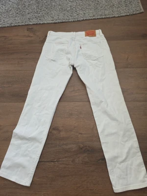 Raka jeans från Levi's - Säljer ett par klassiska vita jeans från Levi's med rak passform. Jätte fint skick. Tillverkade i bomull med metallnitar och knappgylf. Perfekta för en clean och stilren look. W31 L32.