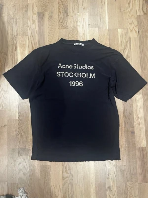 Acne Studios Stockholm 1996 t-shirt - Klassiskt tryck från Acne. Passar perfekt till det mesta! Tröjan är i mycket fint skick, hålen(distressingen) runt kragen och ärmarna är en del av designen. KÖPT PÅ BYXSHOPEN!