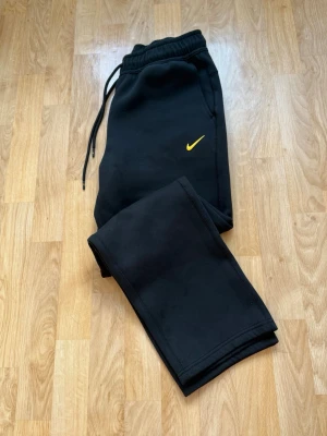 Nocta x Nike byxor - Säljer ett par svarta byxor från Nike x Nocta. Byxorna har resår i midjan med dragsko, raka ben och en ficka med dragkedja på sidan. Perfekta för chill eller streetwear-stil. Ett liten reva på sista bilden men knappt syns. XL men passar de som bara har Large.