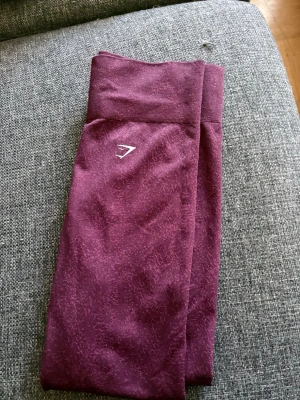 Vinröda seamless leggings från Gymshark - Snygga vinröda seamless leggings från Gymshark med hög midja och diskret mönster i tyget. Stretchigt material som sitter tajt och bekvämt, perfekt för träning eller chill.