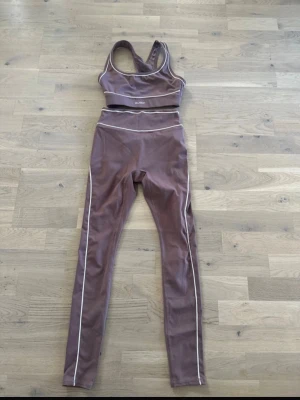 Rosa träningsset från Newyorker - Snyggt rosa träningsset  med sport-bh och höga tights. Setet har vita kontrastsömmar och är gjort i ett stretchigt material som passar perfekt för gym eller yoga. Sport-bhn har racerback och tightsen är fullängd.