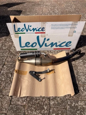 LeoVince avgassystem till moped - Säljer ett LeoVince avgassystem till moped. Systemet är i metall med svart och silverfärgad ljuddämpare och har en böjd form. Monteringsdetaljer och fästen medföljer. Perfekt för dig som vill uppgradera ljud och prestanda på din moppe.