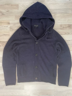 Blå stickad cardigan - Otroligt snygg marinblå stickad cardigan med avtagbar luva. Passar perfekt till kallare väder. Priset kan såklart diskuteras! 