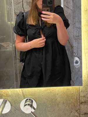 Missäy - Svart kort klänning med puffärm - Svart kort klänning med puffärmar och 3 knyt framtill. Klänningen har en luftig passform