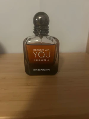 Emporio Armani Stronger With You absolutely  - Emporio Armani Stronger With You Absolutely är en parfym i en elegant glasflaska med mörkbrun och bärnstensfärgad ton. Flaskan har en rundad metallkork och stilren design med tydlig logga framtill. Perfekt för dig som gillar exklusiva dofter. Använd men inte så mycket. 