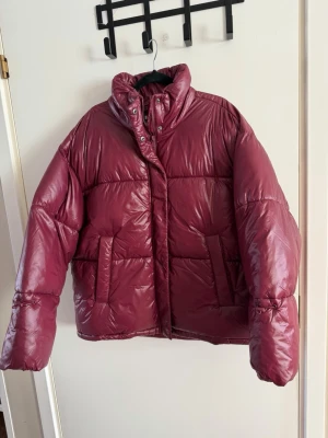 Vinröd pufferjacka stl m - Noisy May glänsande pufferjacka I storlek M, ny med prislapp  Säljer en snygg och trendig pufferjacka från Noisy May. Modellen heter Nmallie Shiny Puffer i färgen Windsor Wine (mörk vinröd eller burgundy med glansig finish).  varm, lätt och perfekt för höst och vinter. Den har dragkedja och tryckknappar framtill samt praktiska fickor. Modern, lite kortare modell som passar till både jeans och mer uppklädda outfits. Upplever den lite over size, så rymlig är den, öppen för bud✨🙌.        nypris 700