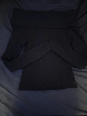 Svart offshoulder ribbad topp - Svart offshoulder topp med ribbad struktur och långa ärmar. Sitter snyggt och tight över axlarna och har en bred kant upptill . .