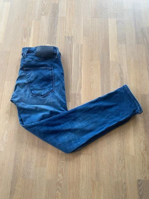 Replay jeans  - Snygga mörkblå jeans med raka ben och klassiska kontrastsömmar. Jeansen har fem fickor och en svart patch bak i midjan. Perfekta för en avslappnad och trendig look. Materialet är bomull med lite stretch. Storlek: W33 L30