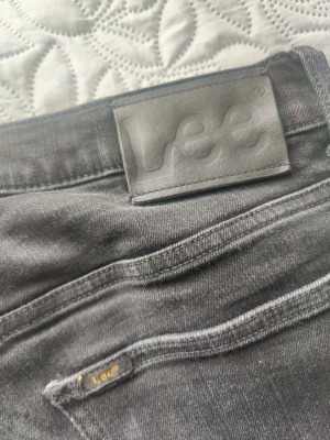 Svarta jeans från Lee - Snygga svarta jeans från Lee med klassisk femficksdesign och raka ben. Jeansen har Lee-logga på bakfickan och läderpatch i midjan. Perfekta för en stilren och avslappnad look.