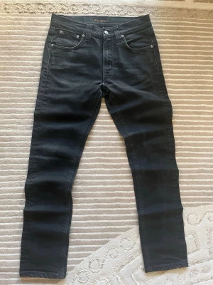  Snygga svarta jeans från Nudie Jeans - Säljer dessa snygga svarta jeans från Nudie Jeans i storlek 30/30. De är i fint skick, använda ett fåtal gånger. Inga hål . Material: 100% bomull. Perfekta för både vardag och fest.