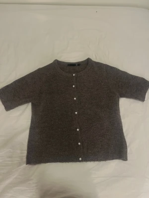 Grå kofta med pärlknappar från lager 157 - Mysig grå kofta från lager 157 med korta ärmar och rund halsringning. Koftan har fina pärlknappar framtill och är stickad i ett mjukt material. Perfekt att slänga på sig över en topp för en chill look.