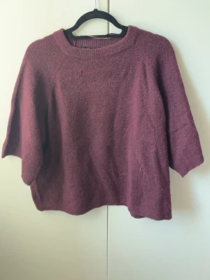 Vinröd stickad tröja från 157 - Vinröd stickad tröja från 157 med avslappnad passform och trekvartsärmar. Tröjan har rund halsringning och är gjord i ett mjukt, grovstickat material som passar perfekt för kyligare dagar. Använd max 2 gånger