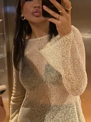 Glittrig guldig fest topp ✨ - Säljer en glittrig guldig fest topp med långärmade och lätt utsvängda ärmar. Toppen har en transparent mesh-look. Perfekt för dig som vill sticka ut med en unik och trendig stil. Storlek s/xs