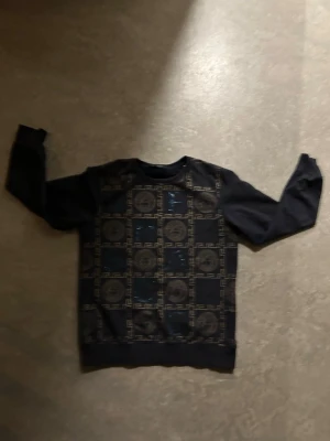 Svart mönstrad sweatshirt - Cool svart sweatshirt med rund hals och unikt geometriskt mönster framtill. Tröjan har långa ärmar och ribbade muddar vid ärmslut och nederkant. Perfekt för dig som vill ha en stilren men ändå iögonfallande look.