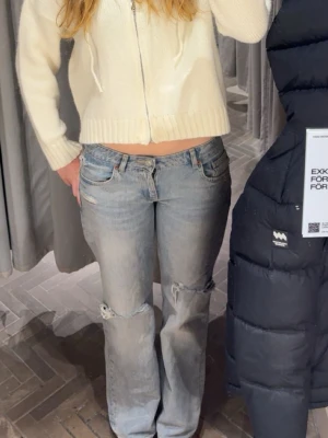 Ljusblå slitna raka jeans - Säljer ett par slutsålda ljusblåa jeans från zara med raka ben och slitningar vid knäna. Jeansen har klassisk femficksdesign och låg midja. Perfekta för en avslappnad och trendig look.