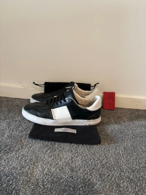 Valentino flycrew - Snygga sneakers från Valentino i svart och vitt läder. Klassisk låg modell med svarta skosnören och vit sula. Skorna har en stilren design med kontrasterande paneler och diskret logga på sidan. Perfekta för dig som vill ha en exklusiv touch till din outfit. Storlek 40/41. Pris kan diskuteras. Äkta.