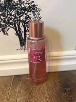 Victoria's Secret Petal Buzz parfym - Fräsch och blommig parfym från Victoria's Secret i doften Petal Buzz. Flaskan är cylinderformad i genomskinligt rosa plast med en elegant roséguldig kork. Doften har inslag av grapefrukt och rosa peppar, perfekt för dig som gillar fruktiga och blommiga toner. Lite mer än hälften kvar!💓🌸