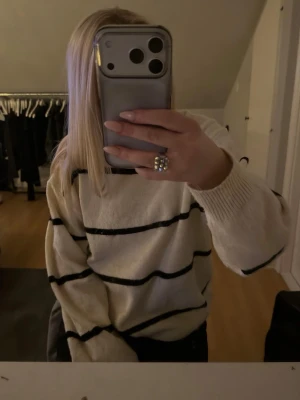 Vit/beige stickad tröja med svarta ränder - Säljer en vit/beige stickad tröja med svarta horisontella ränder. Tröjan har rund halsringning, långa ärmar och en avslappnad passform. Materialet är mjukt och mysigt, perfekt för kyligare dagar men funkar när som. Storlek är xs men passar större och mindre. Skriv privat för bättre bilder