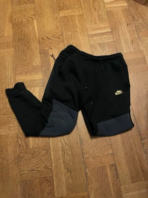 Svarta nike tech byxor - Säljer nike tech byxor som är suveräna för en skön känsla och stilig känsla till och med, dock, har en av snörena gåt lite sönder, men hoppas på att det inte stör mycket, PRIS KAN DISKUTERAS!!!
