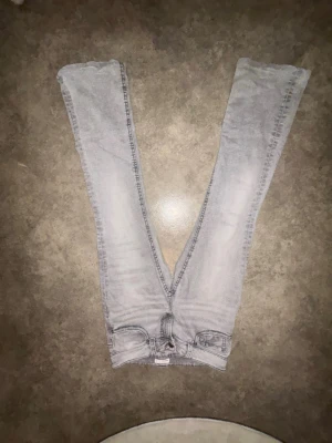 Ljusgrå bootcut  jeans - Säljer ett par ljusgrå bootcut  jeans med klassisk femficksdesign och dragkedjegylf. Jeansen har smal passform och är perfekta för en avslappnad men ändå trendig look. Materialet är mjukt och stretchigt för extra komfort.