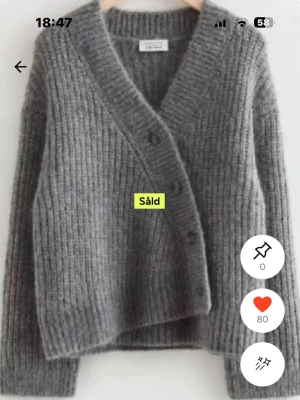 Grå ribbstickad kofta Othor stories - Mysig ribbstickad kofta från othor stories i en mjuk grå nyans. Koftan har v-ringning, stora knappar framtill och långa ärmar. Perfekt för lager på lager och enkel att styla till olika outfits.