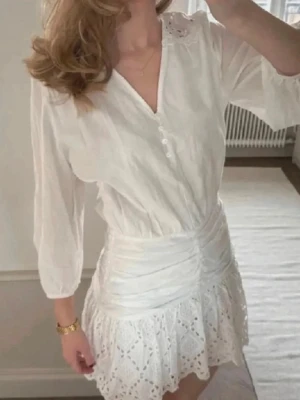Vit kortklänning med spetsdetaljer - Söt vit kortklänning med v-ringning, knappar framtill och trekvartsärm. Perfekt till student och sommar!!🤍🤍