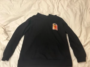 Svart sweatshirt från Casablanca - Cool svart sweatshirt från Casablanca med färgglatt grafiskt tryck på bröstet och stor design på ryggen. Tröjan har rund hals, långa ärmar och ribbade muddar. Perfekt för dig som gillar streetwear och unika prints. 