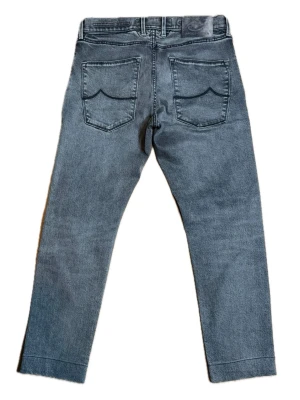 Grå raka jeans med bakfickor - Säljer ett par grå jeans med raka ben och två bakfickor med vågig söm. Jeansen har bälteshällor och klassisk femficksdesign. Materialet är denim i bomull. Perfekta för en avslappnad och trendig look. Nypris 5399