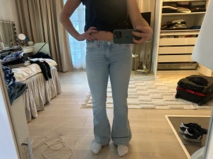 Ljusblå bootcut jeans - Säljer ett par ljusblå bootcut jeans med hög midja och råa kanter nertill. Jeansen har klassisk femficksdesign och är tillverkade i denim med lite stretch för skön passform. Perfekta till sneakers eller boots.