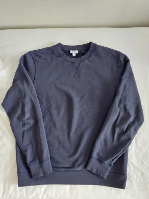 Sunspel sweatshirt / tröja med u-ringad krage - Bild 1 fånga färgen bäst - ett mellanting av marinblå och indigo. Mjuk och skön tröja i bomull från märket Sunspell. Tygets konstruktion och kvalitet är väldigt bra och nypris är 1799 kr. https://www.careofcarl.se/sv/sunspel-loopback-sweatshirt-navy?