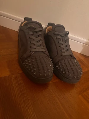 Gråa  Christian Louboutin  - Säljer ett par mörkgråChristian Louboutin med coola nitar över hela tån. Skorna har en klassisk låg siluett, rund tå och matchande mörkgrå snörning. . Perfekta för dig som vill sticka ut med din stil. Några taggar e lite slitna men de kommer med 3 stycken så du kan byta ut några utav dem.Skriv vid funderingar 📲