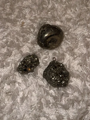 Pyrit - Tre olika pyrit kristaller, två råa och en slipad. En av dem är till för att hänga på ett halsband .