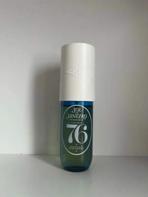 Sol de Janeiro Cheirosa 76 parfym - Fräsch parfym från Sol de Janeiro, Cheirosa 76, i en stilren blågrön glasflaska med stor vit plastkork. Flaskan har en modern design med tydlig logga och siffran 76 framtill. Perfekt för dig som gillar tropiska och somriga dofter. 90 ml