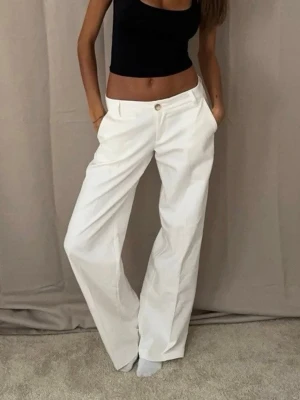 Vita linnebyxor med låg midja och fickor, stl xs - Säljer ett par snygga, vida linnebyxor i vitt med raka ben och låg midja. Byxorna har sidofickor och stängs med knapp och dragkedja framtill. Perfekta för en chill och stilren look. Materialet är lätt och luftigt linneblandning.
