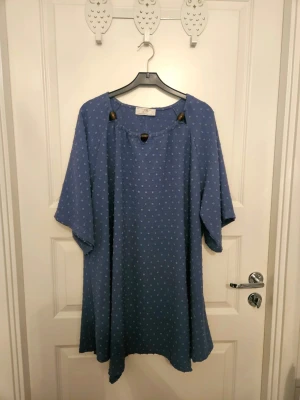 Tunika i storlek 50/52 - Behaglig och snygg blå tunika i a-linjemodell med 3/4-delsärm i mycket gott skick. Bröstmått 130 cm och längd 80 cm. Storlek 50/52. Materialet är en bomullsblandning.