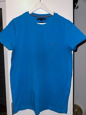 Blå t-shirt Tommy Hilfiger - Snygg blå t-shirt från Tommy Hilfiger i extra slim fit. Klassisk modell med rund hals och korta ärmar. Liten broderad logga på bröstet. Tillverkad i mjuk bomull som känns skön mot huden.