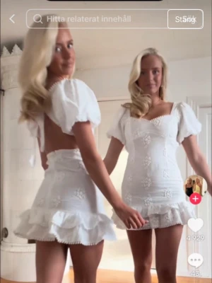 Vit kort klänning med volang - Söt vit kortklänning med puffärmar, volangkant nedtill och broderade blommor. Perfekt till studenten. Klänningen har öppen rygg. Helt ny i stlk 36