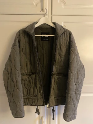 Olivgrön quiltad pufferjacka Zara - Säljer en grå/grön quiltad pufferjacka som är väldigt eftertraktad från Zara! Den är lite smått nopprig på höger sida men det är något som knappt syns. Priset kan absolut diskuteras 💞